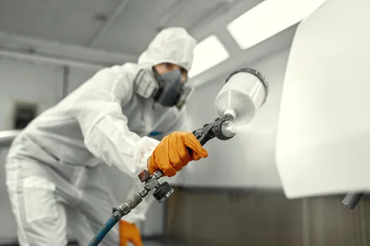 Painter in protective gear spray finishing cabinet doors