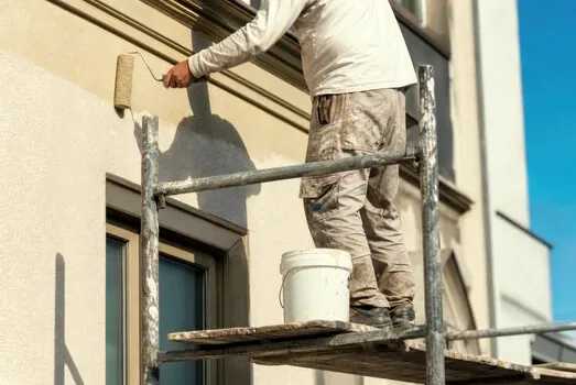 Painter on scaffolding repainting a Mediterranean stucco home in Westlake Village